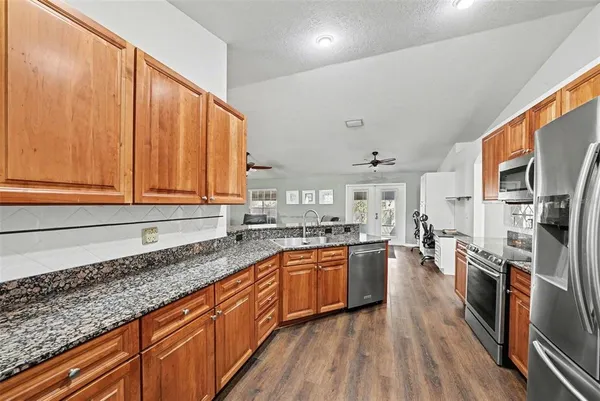 a large kitchen with stainless steel appliances granite countertop a stove a sink dishwasher and a refrigerator with wooden floor