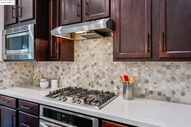 a kitchen with stainless steel appliances granite countertop wooden cabinets a stove a sink and a wooden floors