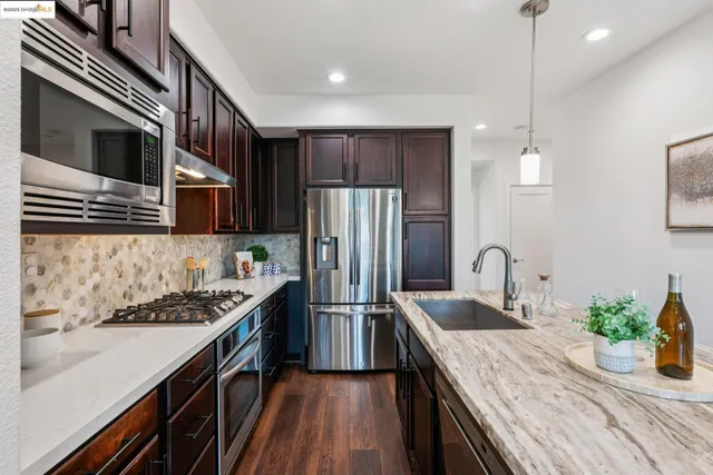 a kitchen with stainless steel appliances granite countertop a refrigerator a sink and wooden cabinets