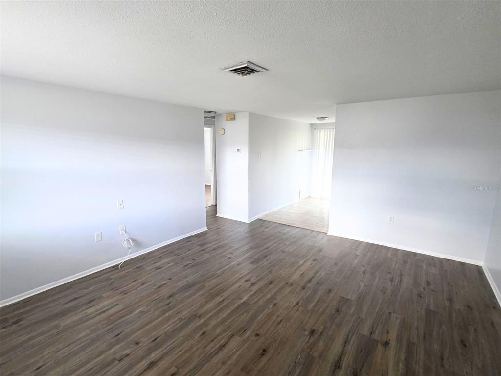 546 Briarwood Road Venice, FL 34293 - Photo 6 of 20 a view of an empty room with wooden floor and a ceiling fan