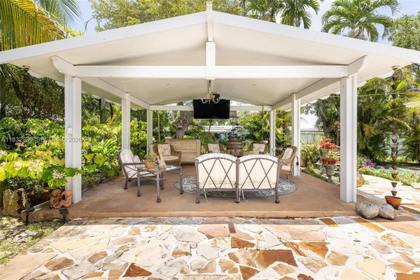 a view of a patio with table and chairs potted plants and floor to ceiling window