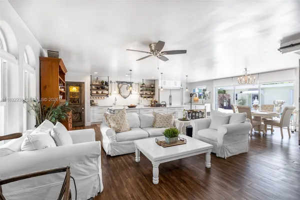 a living room with furniture a ceiling fan and a large window