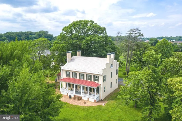 a view of a house with a big yard and large trees