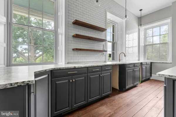 a dining table with a chandelier and kitchen view