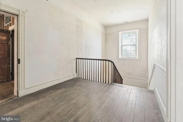 an empty room with wooden floor fireplace and windows