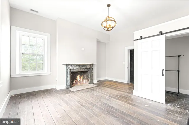 an empty room with wooden floor cabinet and windows