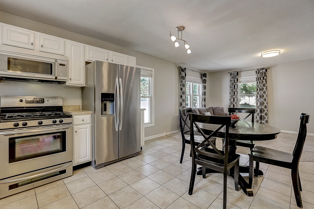 1025 North Main Street Naperville, IL 60563 - Photo 7 of 28 a kitchen with stainless steel appliances granite countertop a stove a refrigerator a microwave a dining table and chairs with wooden floor