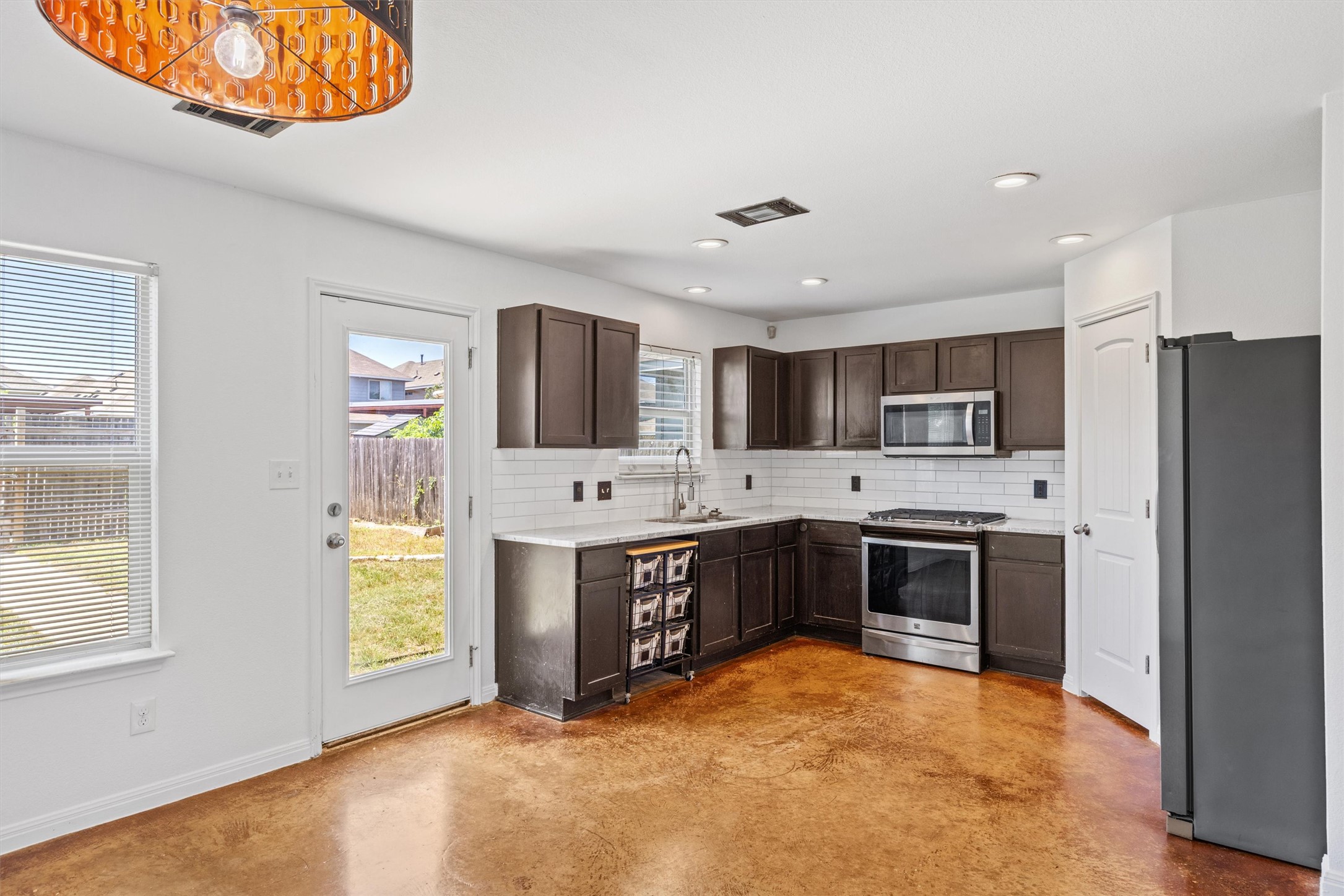 4516 Kind Way, Unit 253 Austin, TX 78725 - Photo 7 of 31 a large kitchen with stainless steel appliances granite countertop a stove refrigerator and a sink