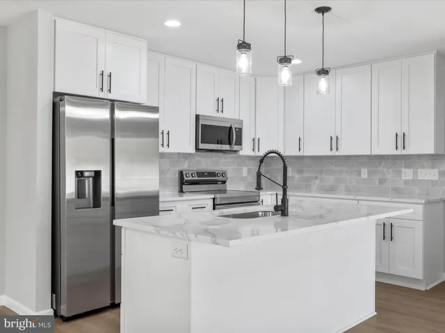 a kitchen with stainless steel appliances granite countertop a refrigerator a sink a stove and white cabinets