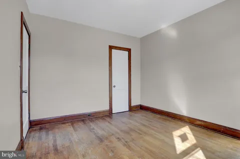 a view of an empty room with wooden floor and closet