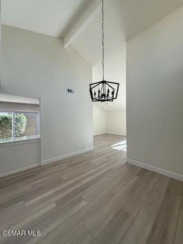 a view of an empty room with window and wooden floor