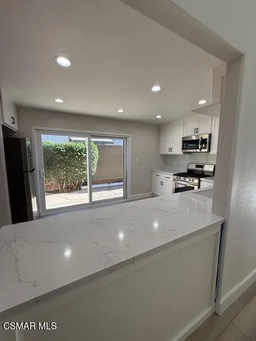 a view of kitchen with stainless steel appliances granite countertop a refrigerator a sink a stove and a refrigerator with wooden floor