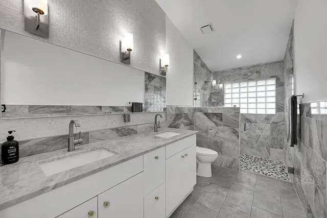 a bathroom with a double vanity sink toilet and a shower