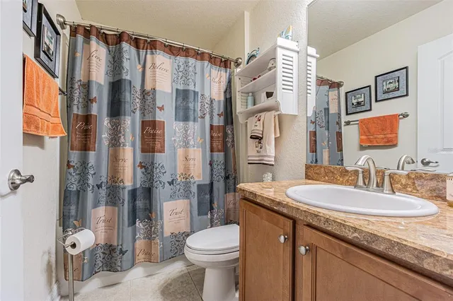 a bathroom with a granite countertop sink a toilet a shower and a mirror