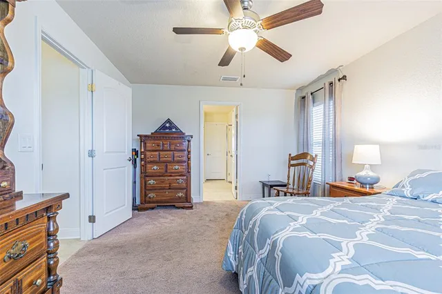 a bedroom with a bed a dresser and a chandelier