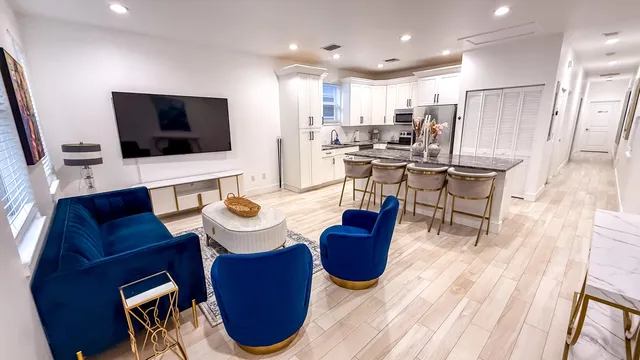 a living room with furniture a flat screen tv and kitchen view