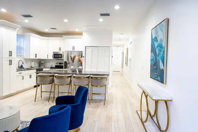 a kitchen with stainless steel appliances kitchen island granite countertop a refrigerator a stove a sink dishwasher with a dining table and chairs with wooden floor