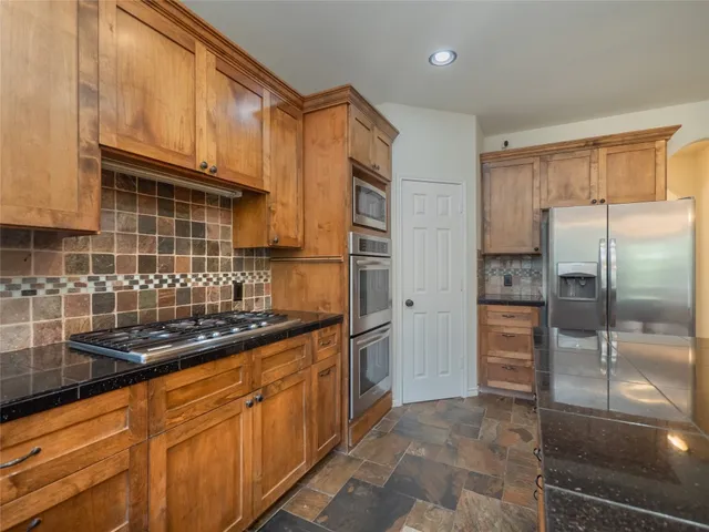a kitchen with stainless steel appliances granite countertop a refrigerator and a sink