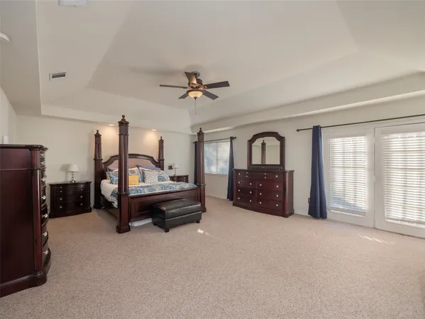 a spacious bedroom with a bed a dresser and a large window