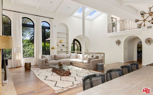 a living room with couches a large mirror with wooden floor and windows