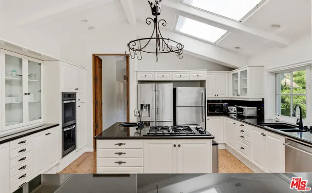 a kitchen with stainless steel appliances a counter space a sink a window and cabinets