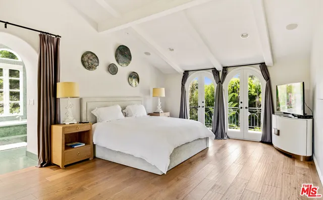 a large white bed sitting in a room next to a window