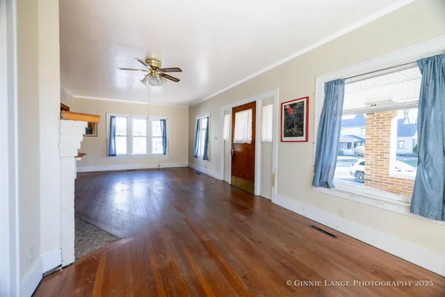an empty room with wooden floor chandelier fan and windows