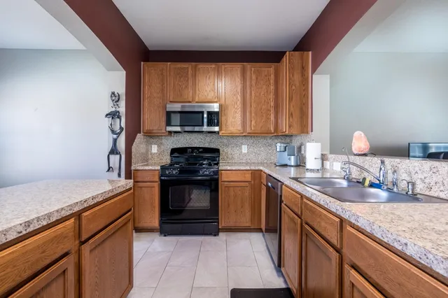 a kitchen with stainless steel appliances granite countertop wooden cabinets a stove top oven a sink and dishwasher