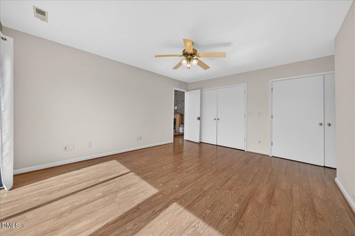 180 Manor Drive Timberlake, NC 27583 - Photo 16 of 85 a view of an empty room with wooden floor and a ceiling fan