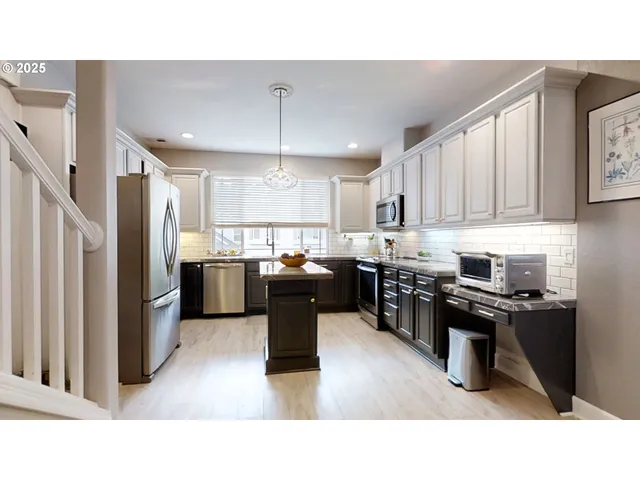 a kitchen with stainless steel appliances granite countertop a sink a stove a refrigerator cabinets and a window