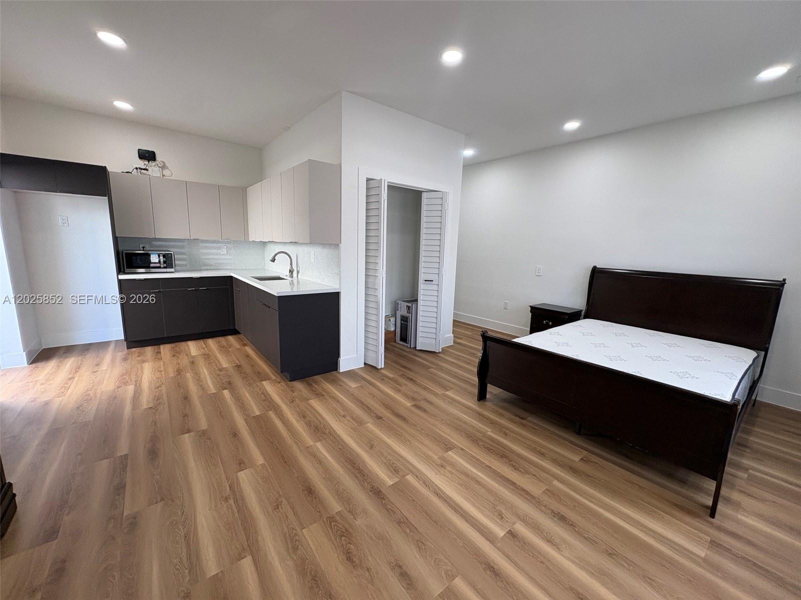 12948 Southwest 265th Terrace, Unit STUDIO Homestead, FL 33032 - Photo 11 of 16 a large kitchen with stainless steel appliances wooden floors and wooden cabinets