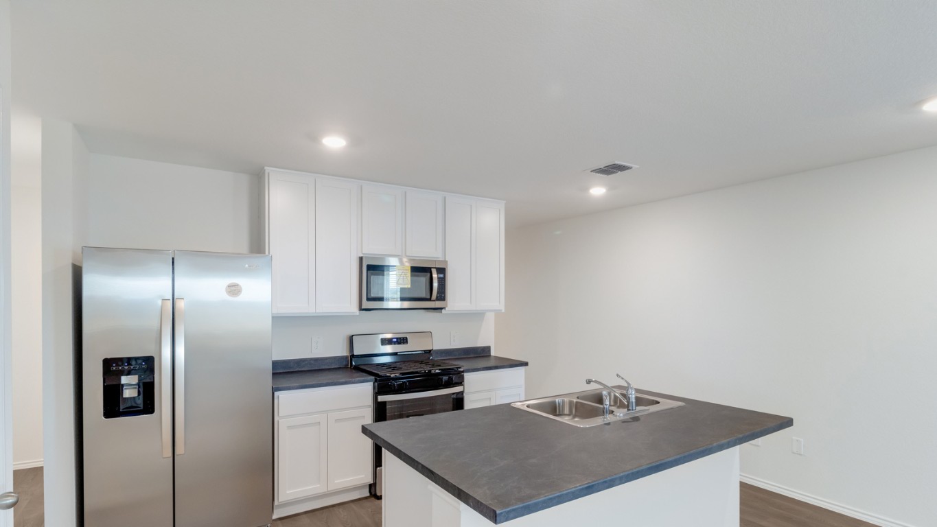 345 Bull Lake Circle Buda, TX 78610 - Photo 5 of 17 a kitchen with stainless steel appliances a stove a refrigerator a sink a stove with white cabinets