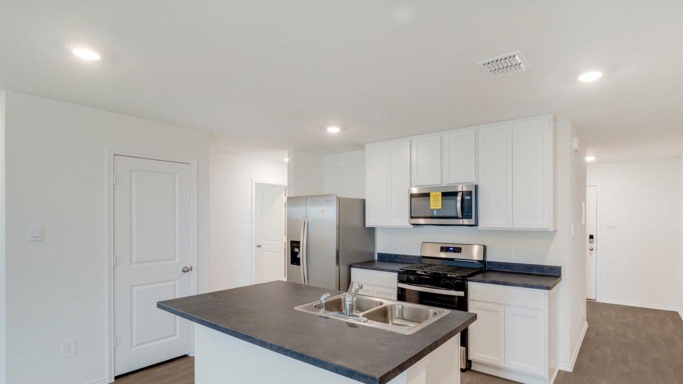 345 Bull Lake Circle Buda, TX 78610 - Photo 6 of 17 a kitchen with stainless steel appliances granite countertop a sink stove and refrigerator
