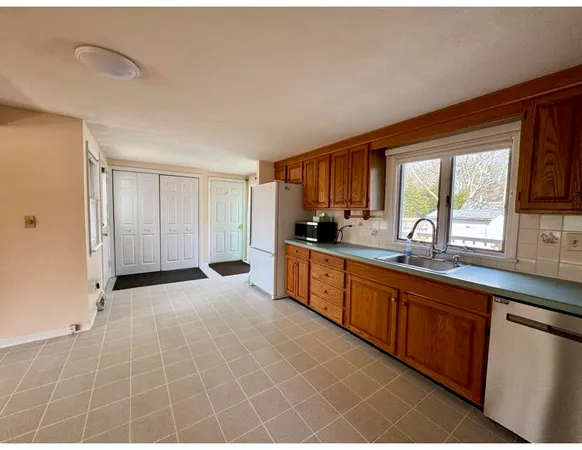 a large kitchen with granite countertop a stove a sink a window and cabinets