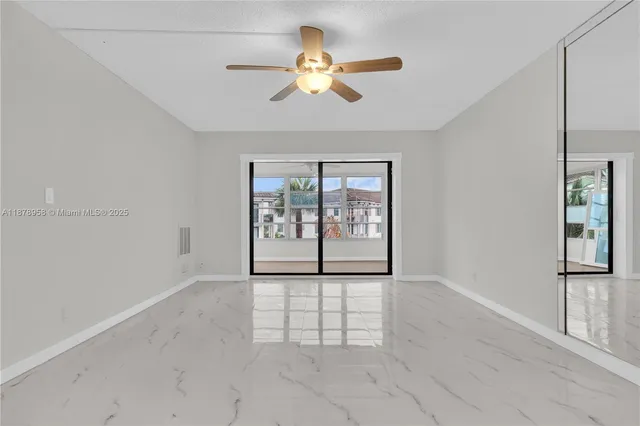 an empty room with windows and fan