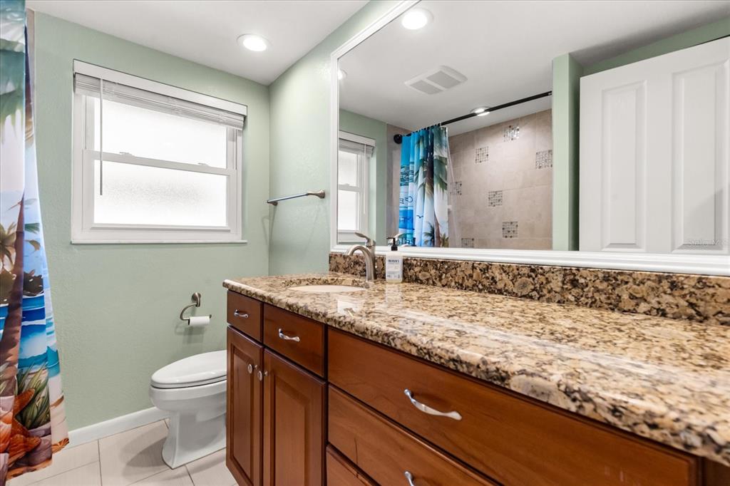 620 Jacaranda Street Dunedin, FL 34698 - Photo 17 of 30 a bathroom with a granite countertop sink a toilet and a mirror