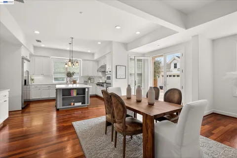a kitchen with stainless steel appliances kitchen island granite countertop a dining table chairs and white cabinets