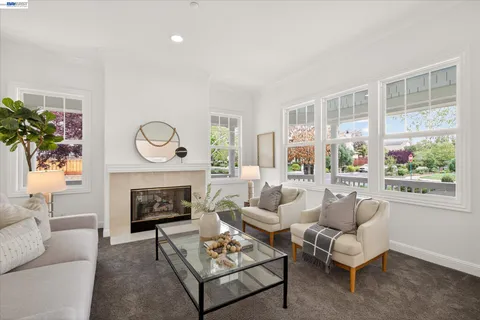 a living room with furniture a fireplace a table and a large window