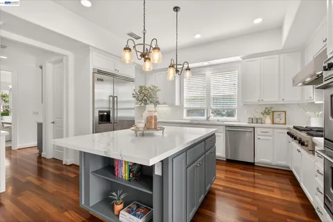 a kitchen with kitchen island granite countertop a stove a sink a refrigerator and wooden floor
