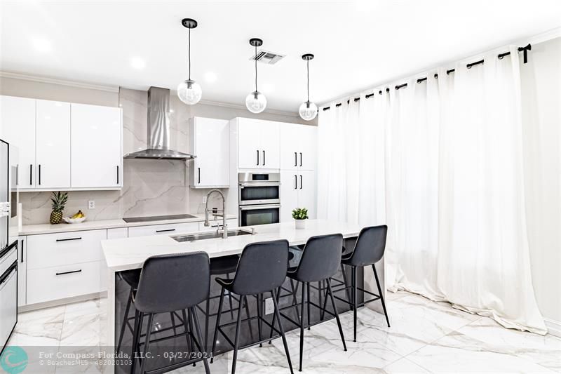 a kitchen with stainless steel appliances kitchen island granite countertop a table chairs and a white cabinets