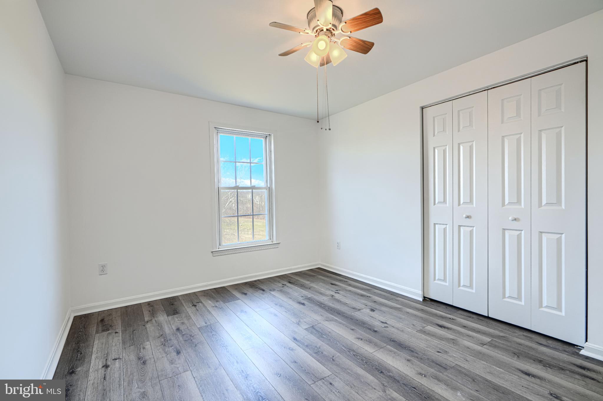 1216 Bachmans Valley Road Westminster, MD 21158 - Photo 33 of 70 an empty room with wooden floor chandelier fan and windows