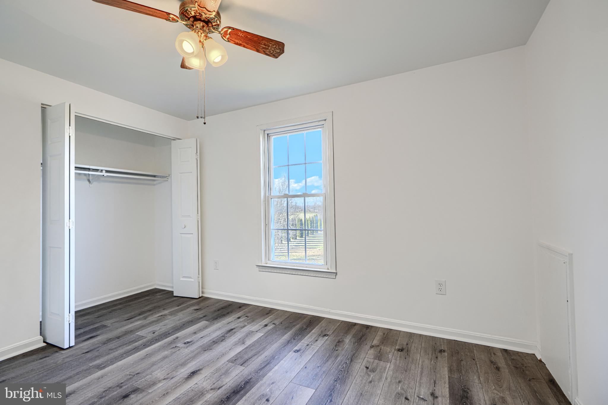 1216 Bachmans Valley Road Westminster, MD 21158 - Photo 38 of 70 an empty room with wooden floor chandelier fan and windows