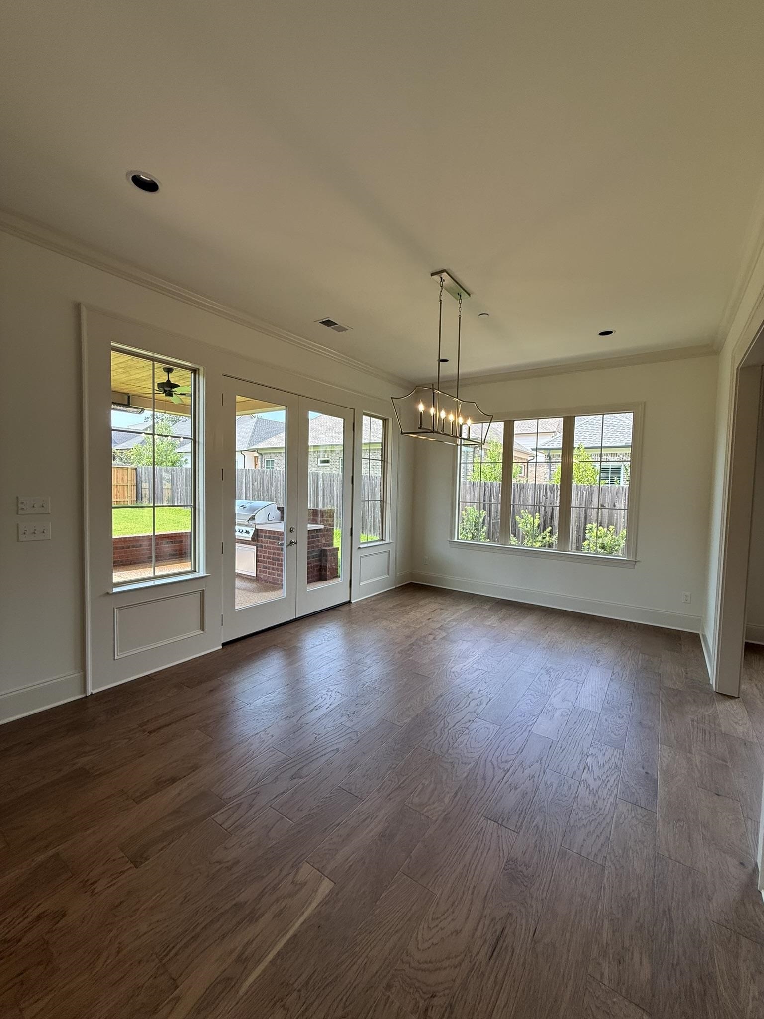 10132 Rokeby Farm Lane Collierville, TN 38017 - Photo 8 of 24 Spacious room featuring wood-finish flooring, ample natural light from multiple windows and French doors, a modern linear chandelier, recessed lighting, and crown molding