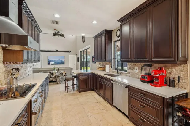 a kitchen with granite countertop lots of counter top space a sink stainless steel appliances and cabinets