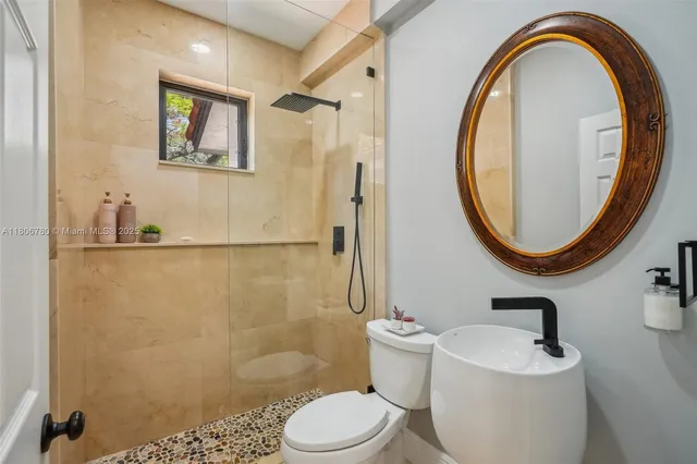 a bathroom with a sink a mirror a toilet and a shower