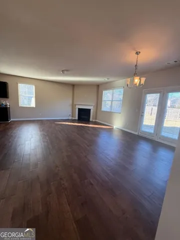 an empty room with wooden floor fireplace and windows