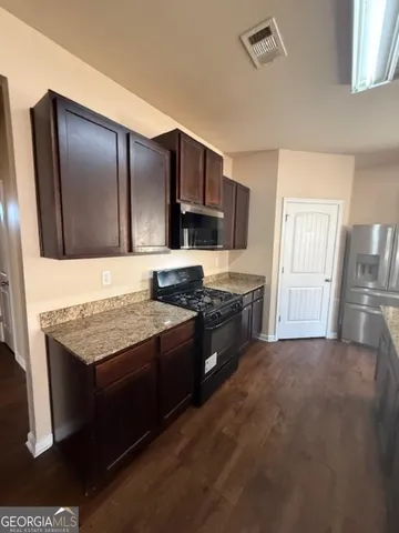 a kitchen with stainless steel appliances granite countertop a stove refrigerator and cabinets