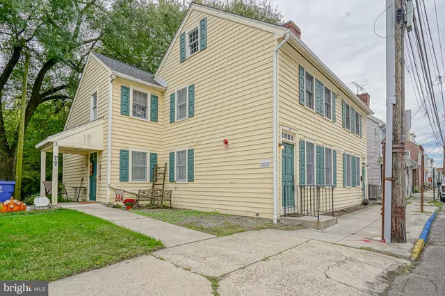 a view of a white house with a yard and table and chairs next to window