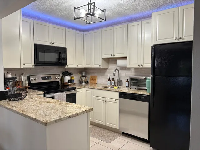 a kitchen with stainless steel appliances granite countertop a refrigerator stove top oven a sink and dishwasher