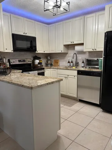 a kitchen with stainless steel appliances granite countertop a stove a sink and a microwave